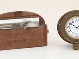 une petite horloge posée à côté d'une boîte sur laquelle est fixé un miroir