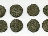 six pièces de monnaie romaines sont alignées sur une surface blanche