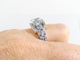 a woman ' s hand holding a diamond and blue sapphire ring