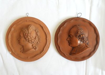 two plaques of women in profile on a white surface