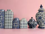 many blue and white vases and jars on a pink surface