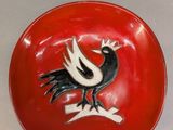 un bol rouge orné d'un oiseau noir et blanc