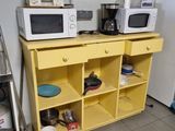 two microwaves on a yellow shelf in a kitchen