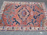 un tapis oriental posé au sol, orné d'un motif rouge et bleu