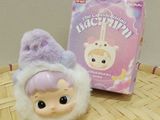 a small doll sitting next to a box on a table