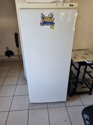 un réfrigérateur blanc dans une petite cuisine au sol carrelé