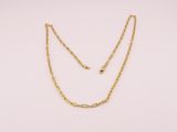 un collier à chaîne en or orné d'une boule sur fond blanc