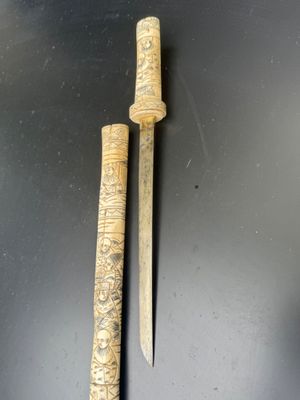 pair of carved wooden knives on a black surface with a black background