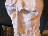une sculpture représentant une tête d'homme posée sur une table en bois