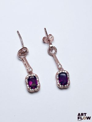 une paire de boucles d'oreilles ornées de pierres violettes sur fond blanc