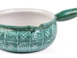 a green bowl with a spoon in it on a white surface
