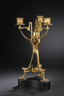 un candélabre ancien en laiton à quatre bougies, posé sur un socle en marbre