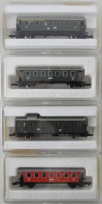 quatre wagons de train dans des conteneurs en plastique posés sur une surface blanche