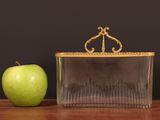 a green apple next to a clear purse on a table