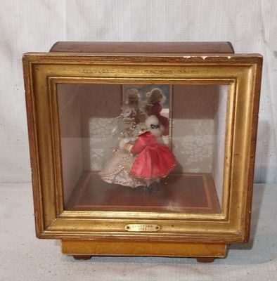 une poupée miniature dans une vitrine posée sur une table