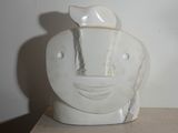 un vase blanc orné d'un visage, posé sur une table