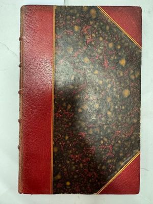 un vieux livre à la couverture rouge posé sur une surface blanche