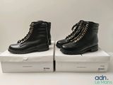 two pairs of black boots with gold chains on them sitting on a box