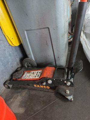 une trottinette noire et orange posée par terre à côté d'une poubelle