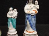 three figurines of a woman holding a baby and a man holding a child
