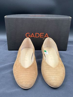 une paire de chaussures beiges avec une boîte sur un fond bleu