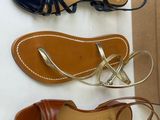 two pairs of sandals and a box on a white surface