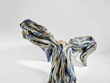 un gros plan d'une sculpture représentant un oiseau sur une surface blanche