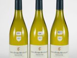 trois bouteilles de vin blanc posées l'une à côté de l'autre sur une surface blanche