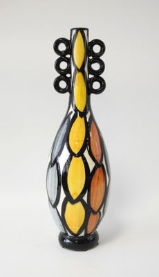 un vase noir et jaune posé sur une surface blanche