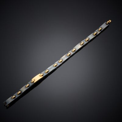 a close up of a black and gold bracelet on a black background