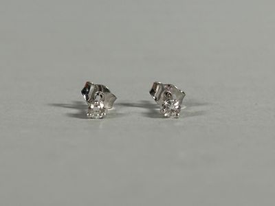a pair of diamond stud earrings sitting on top of a table
