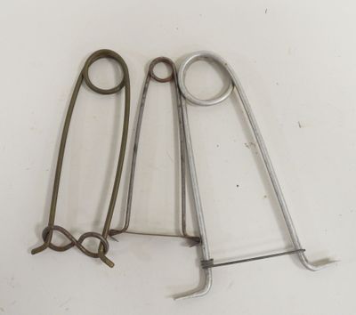 trois paires d'instruments chirurgicaux sont posées sur une surface blanche