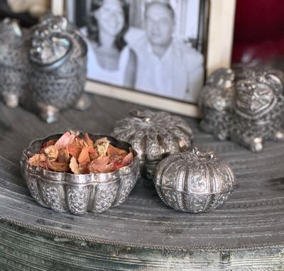 a bowl of dried flowers on a table next to a picture of a woman