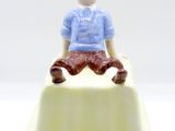 a small figurine of a man sitting on top of a cake