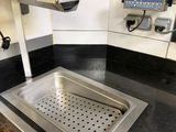stainless steel sink in a commercial kitchen with black counter tops