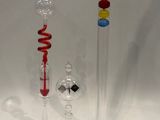 trois vases en verre de couleurs différentes posés l'un à côté de l'autre sur une surface blanche