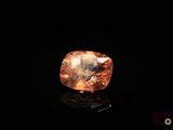 an orange diamond on a black surface in the dark