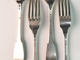 four forks and a spoon on a white table