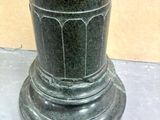 a green vase sitting on top of a table next to a wall