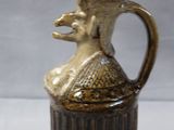 a brown vase with a bird on it on a table