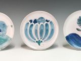 three plates with blue and green designs on them on a white surface