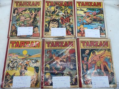 Plusieurs bandes dessinées sont alignées sur une table, à côté d'une pancarte