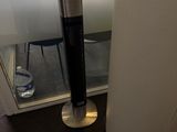 une enceinte noire et argentée posée sur un pied près d'une fenêtre
