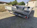 a flat bed trailer parked in a gravel lot