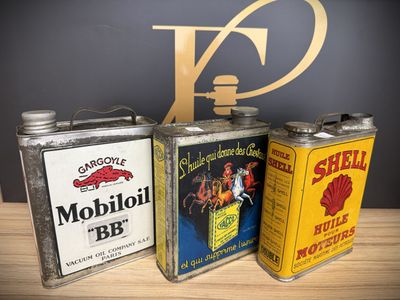 three cans of oil are sitting on a table next to a sign