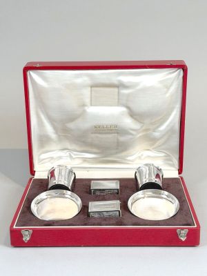 une paire de tasses plaquées argent dans un coffret rouge posé sur une surface blanche