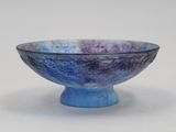 un bol bleu et violet posé sur une surface blanche