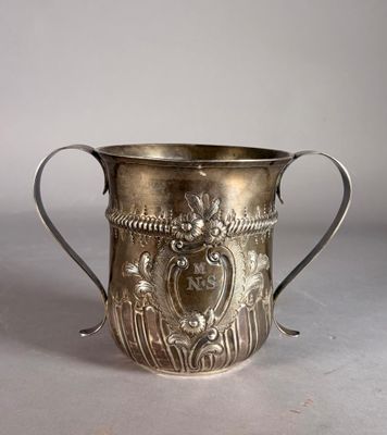an old silver cup sitting on top of a table next to a white wall