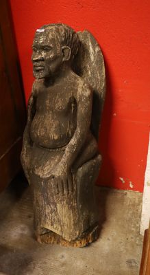 a statue of a woman sitting on a chair next to a red wall