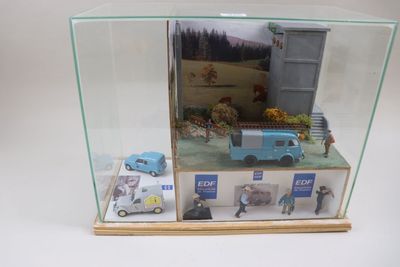 une vitrine en verre contenant un camion miniature et d'autres véhicules miniatures
